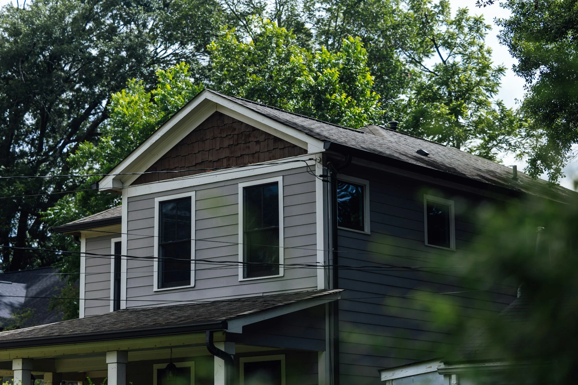 Gray house with new siding surrounded by trees