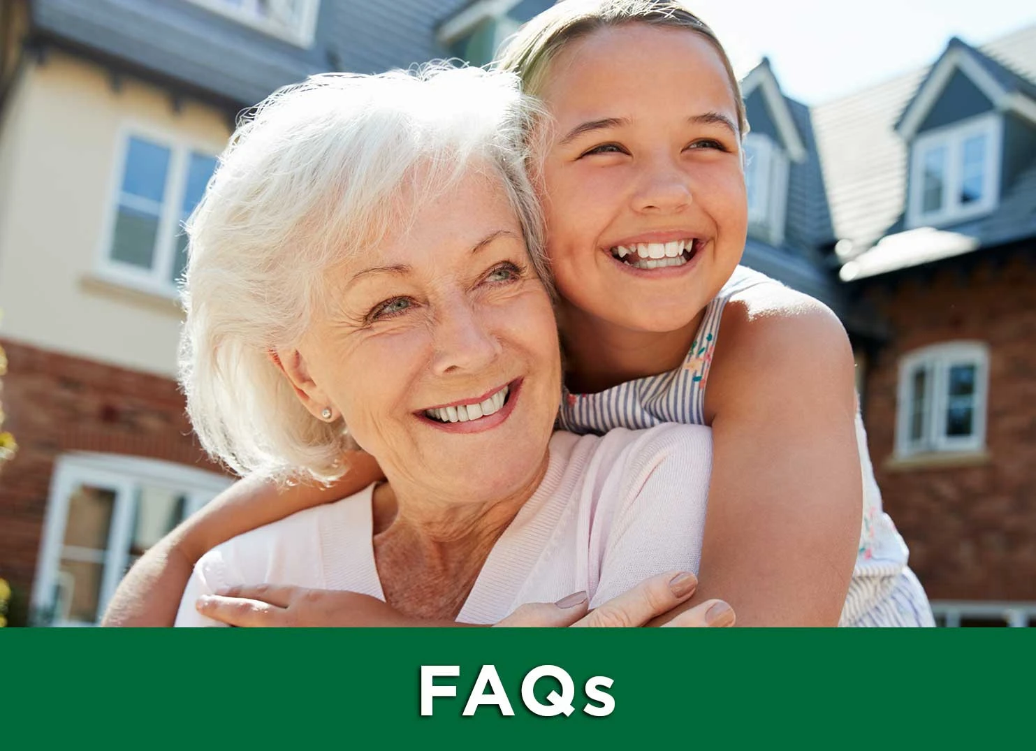 Grandmother and granddaughter smiling and hugging outdoors