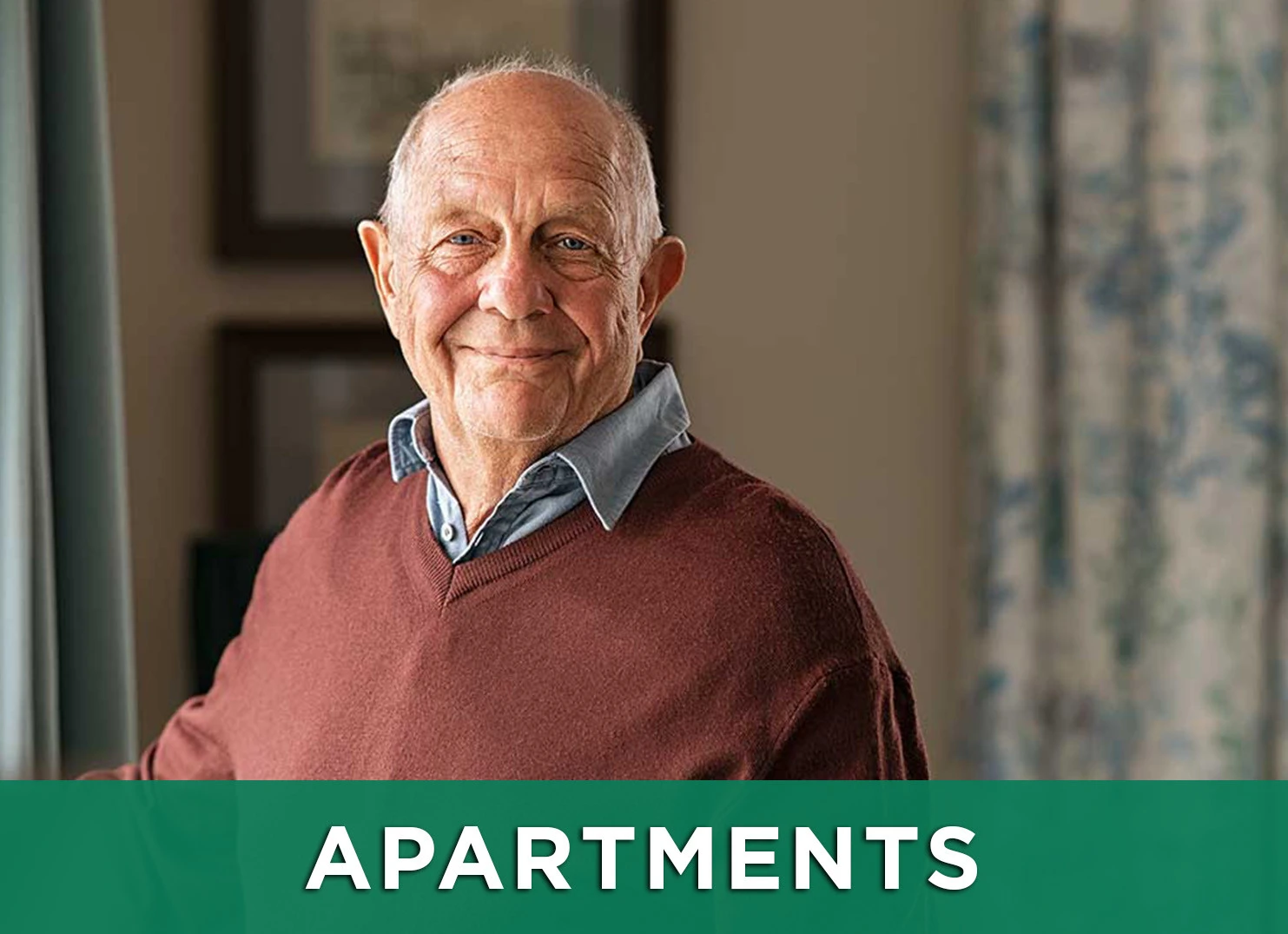 Image: Senior man smiling inside his apartment with a link to the Apartments page for more information
