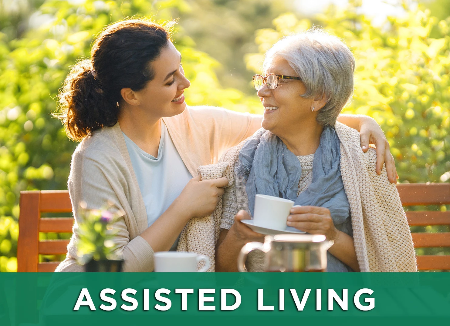 Image: Daughter and senior woman on park bench enjoying tea with a link to the Assisted Living page.