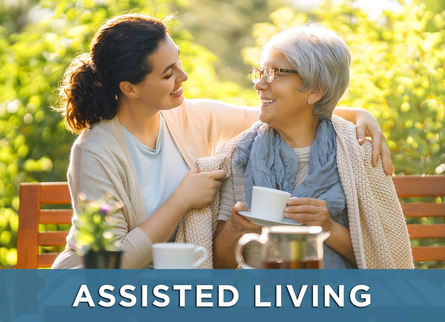 Image of senior woman and caretaker on park bench smiling with a link to the Assisted Living page for more information