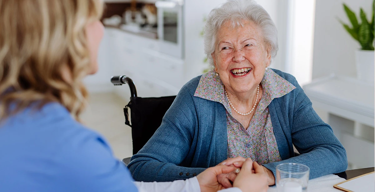 Elderly man smiling up at caretaker in nursing home