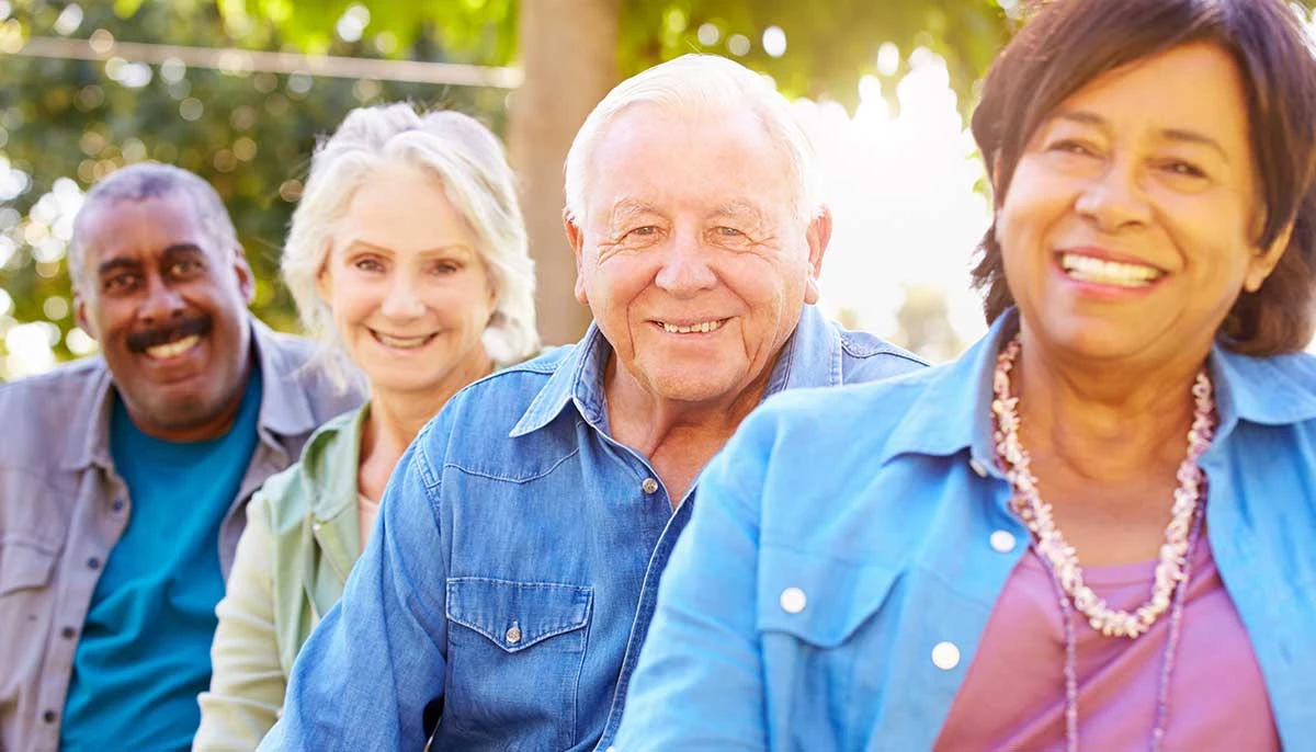 Elderly man in wheelchair drinking tea and talking to nurse in assisted living facility