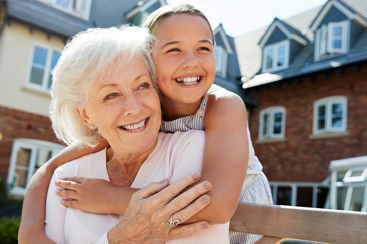 Grandmother and granddaughter hugging and smiling in a courtyard