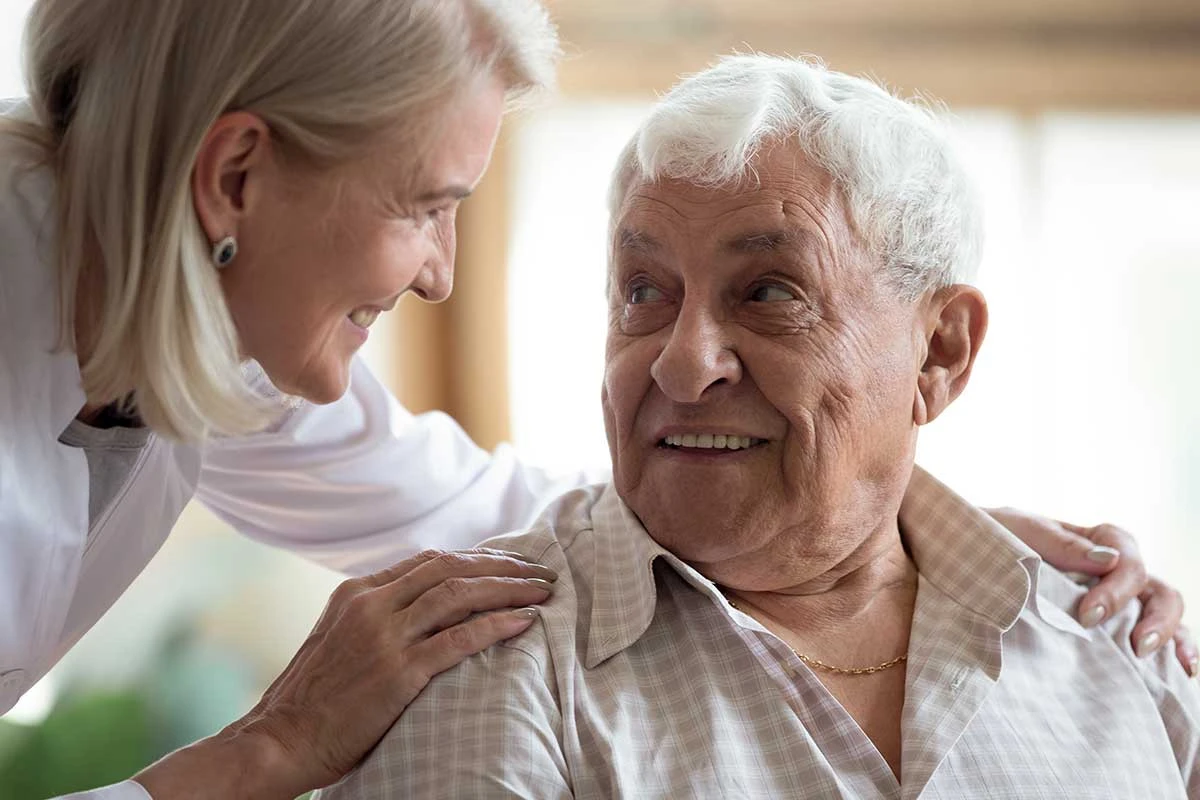 Elderly man smiling up at caretaker in nursing home