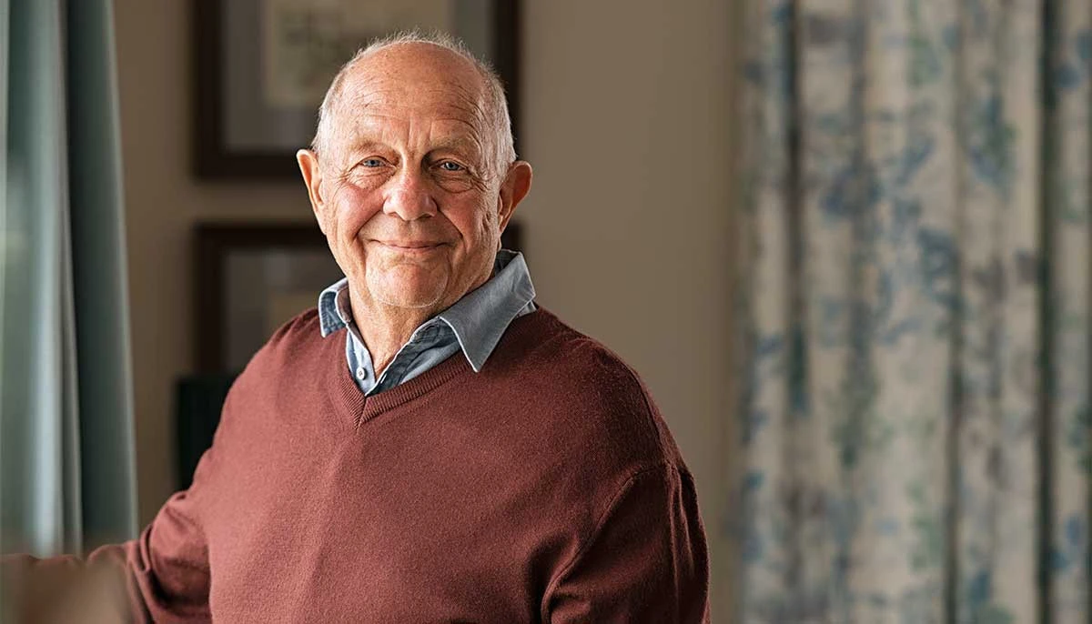 Elderly man proudly standing in his assisted living apartment