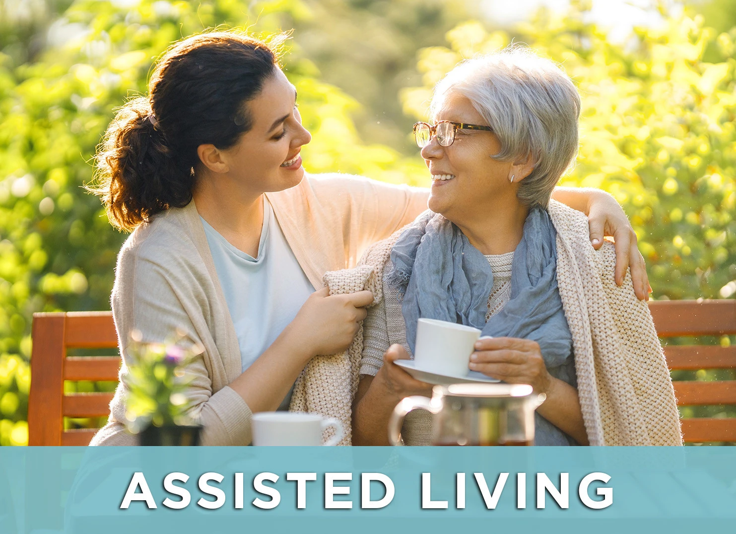Image of senior woman and caretaker smiling on a park benchwith a link to the Assisted Living page for more information