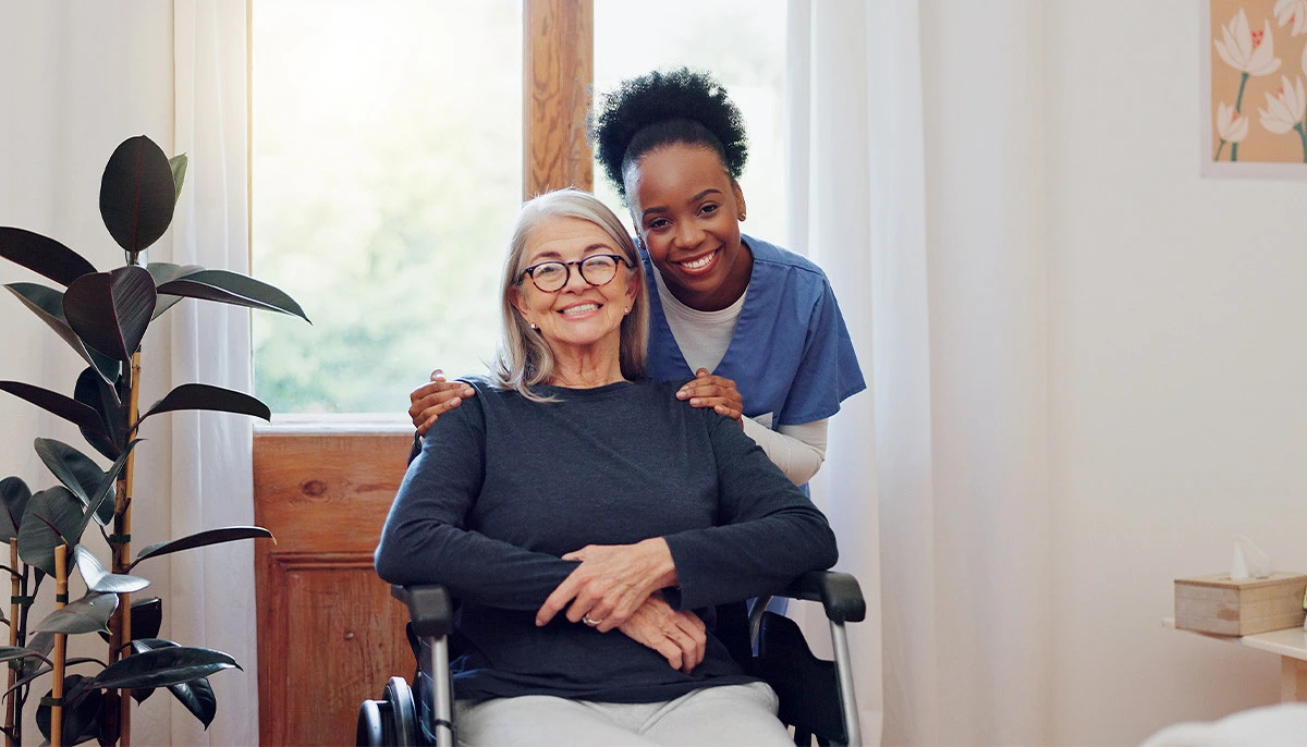 Senior woman in wheelchair talking to nurse in assisted living community