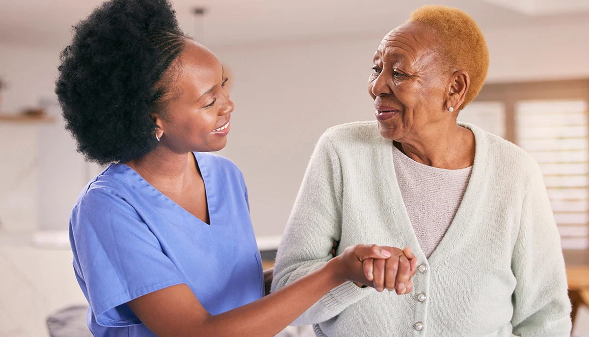 Senior woman in wheelchair talking to nurse in assisted living community