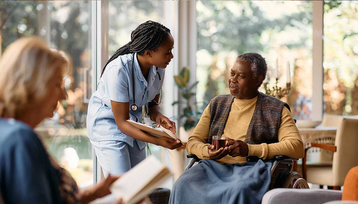Elderly man smiling up at caretaker in nursing home
