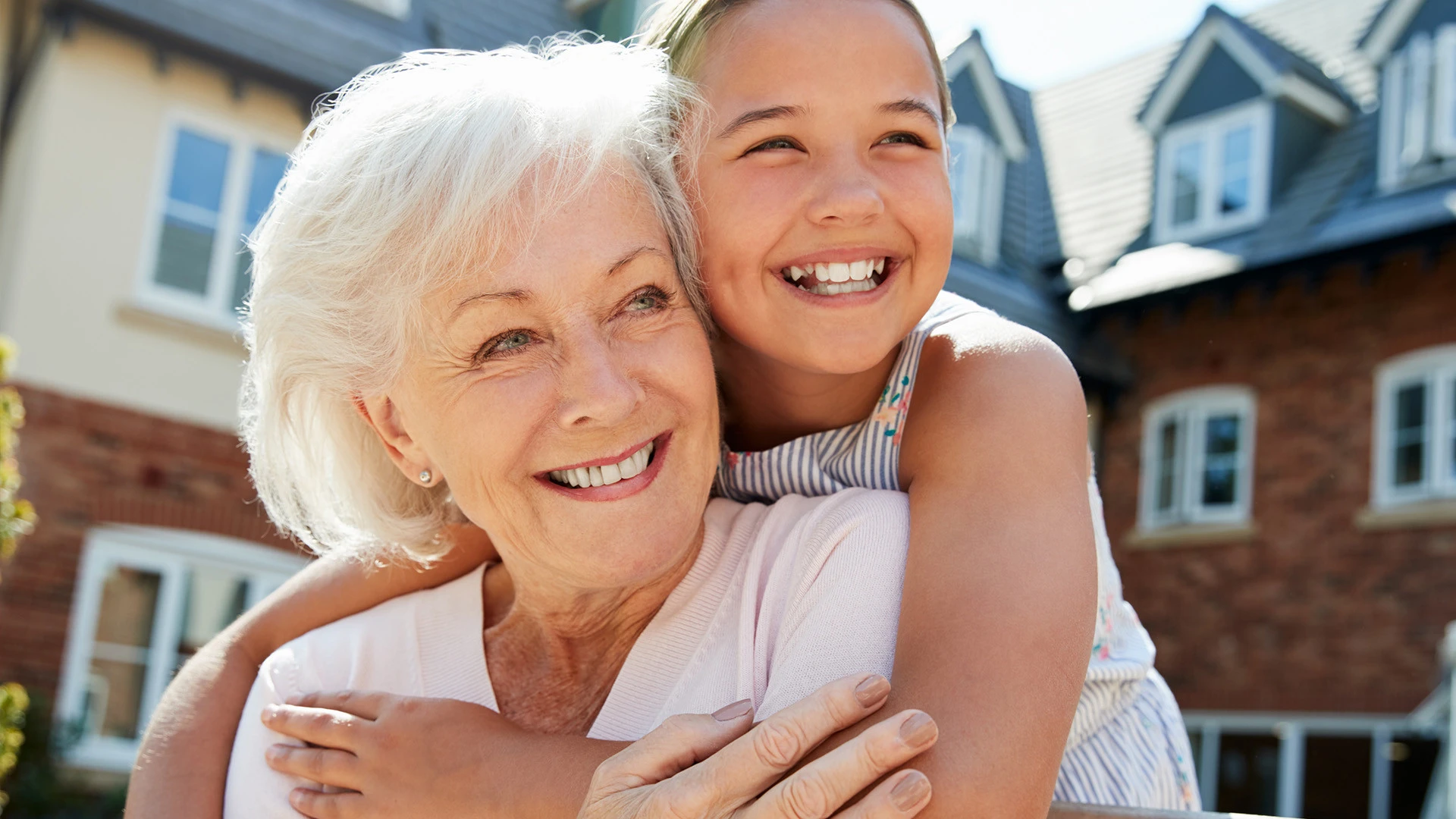 Grandmother and granddaughter hugging and smiling in a courtyard