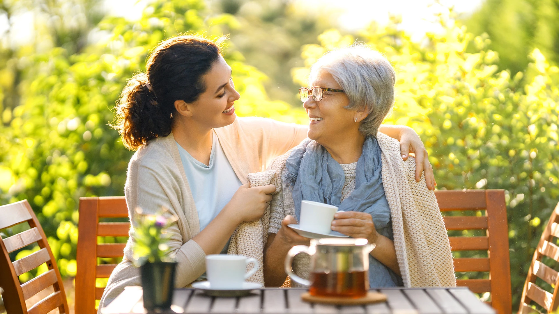 Daughter and elderly mother enjoying tea on an outdoor patio