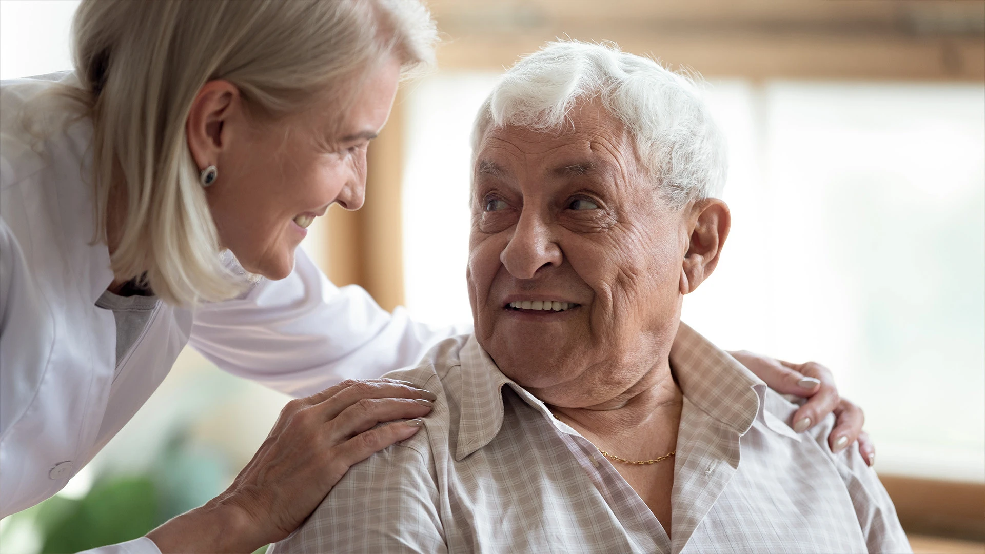 Elderly man smiling up at caretaker in nursing home