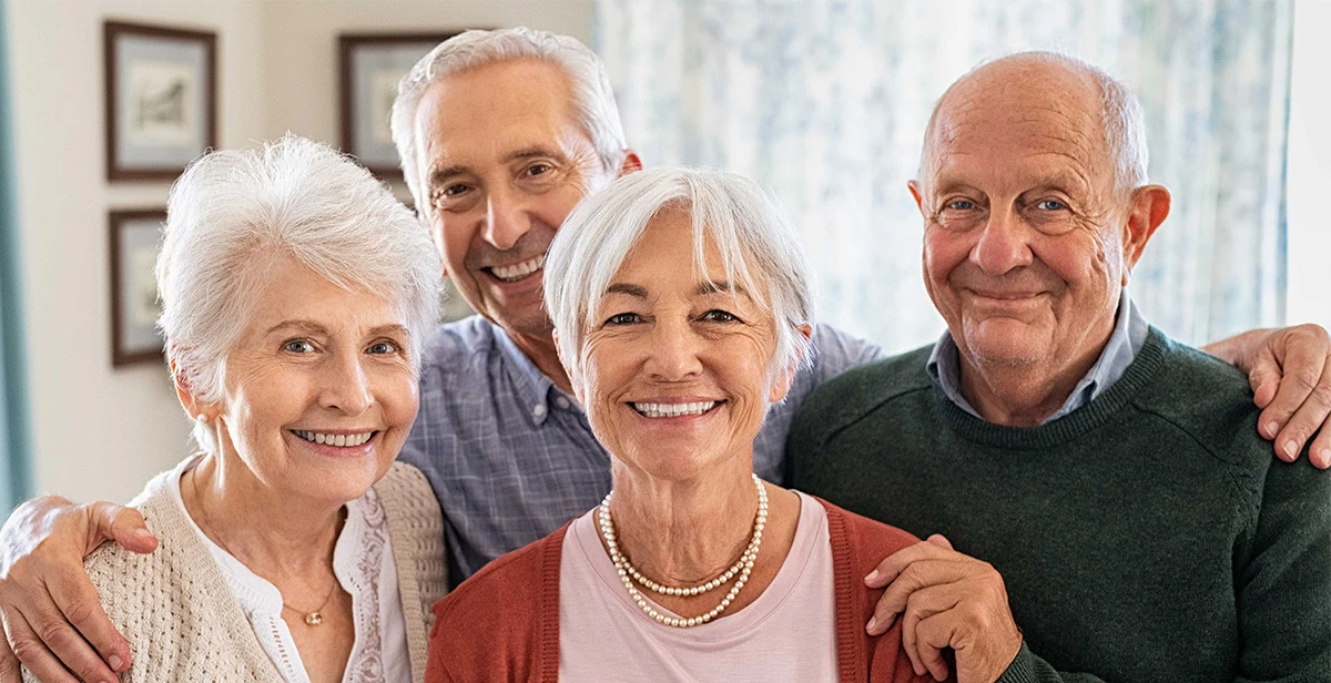 Elderly man in wheelchair drinking tea and talking to nurse in assisted living facility