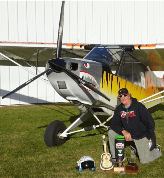Joel Milloway poses in front of his Rans S–7 “Tiger Shark” with all of his winnings.